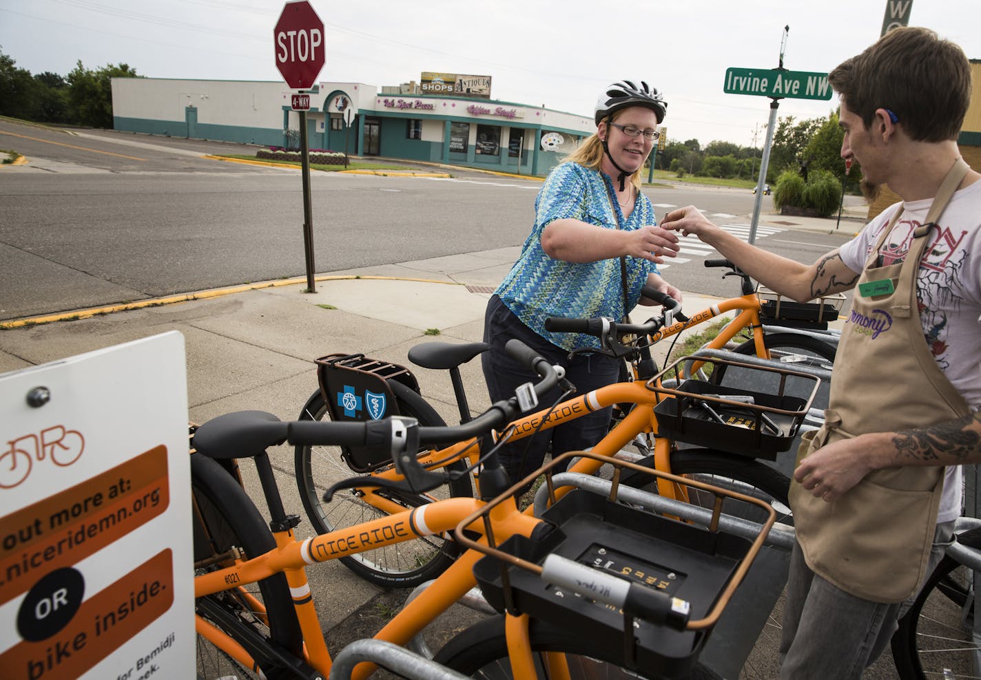 Melinda Neville, the manager of Nice Ride Bemidji, rents a bike from Alex Lundin, right, at Harmony Co-op in Bemidji on Thursday, August 13, 2015. ] LEILA NAVIDI leila.navidi@startribune.com / BACKGROUND INFORMATION: Nice Ride has started a pilot program in Bemidji designed to increase biking in Bemidji by both residents and visitors.