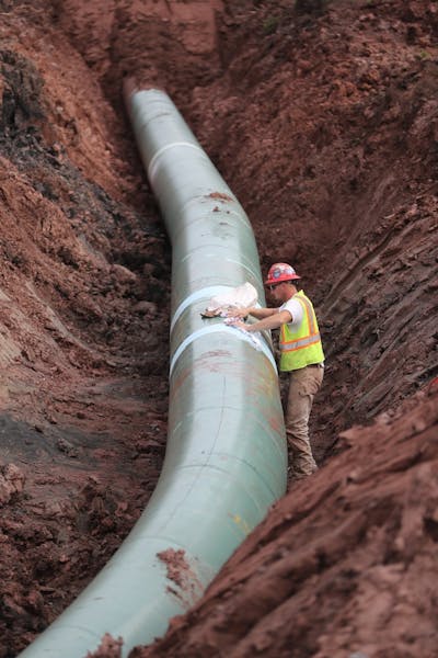 A pipe fitter lays the finish finishing touches to the replacement of Line 3 stretch before it is covered up.