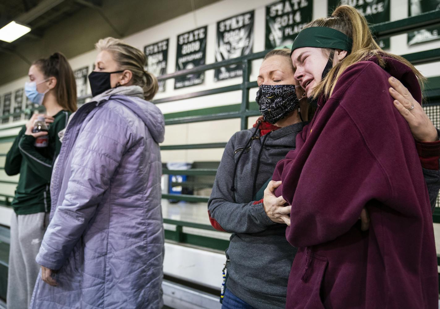 Emma Wasiloski, 13, an eighth grader at North Heights Christian Academy who plays for Concordia Academy's C volleyball team and elite club volleyball, cried in the arms of her mother MaryBeth Wasiloski after hearing the news that the volleyball season would be paused by Governor's orders, while standing for the National Anthem before the varsity volleyball game between Concordia and St. Agnes. "I don't know what I'm going to look forward to," said Emma. "Because school isn't fun anymore." ] LEIL