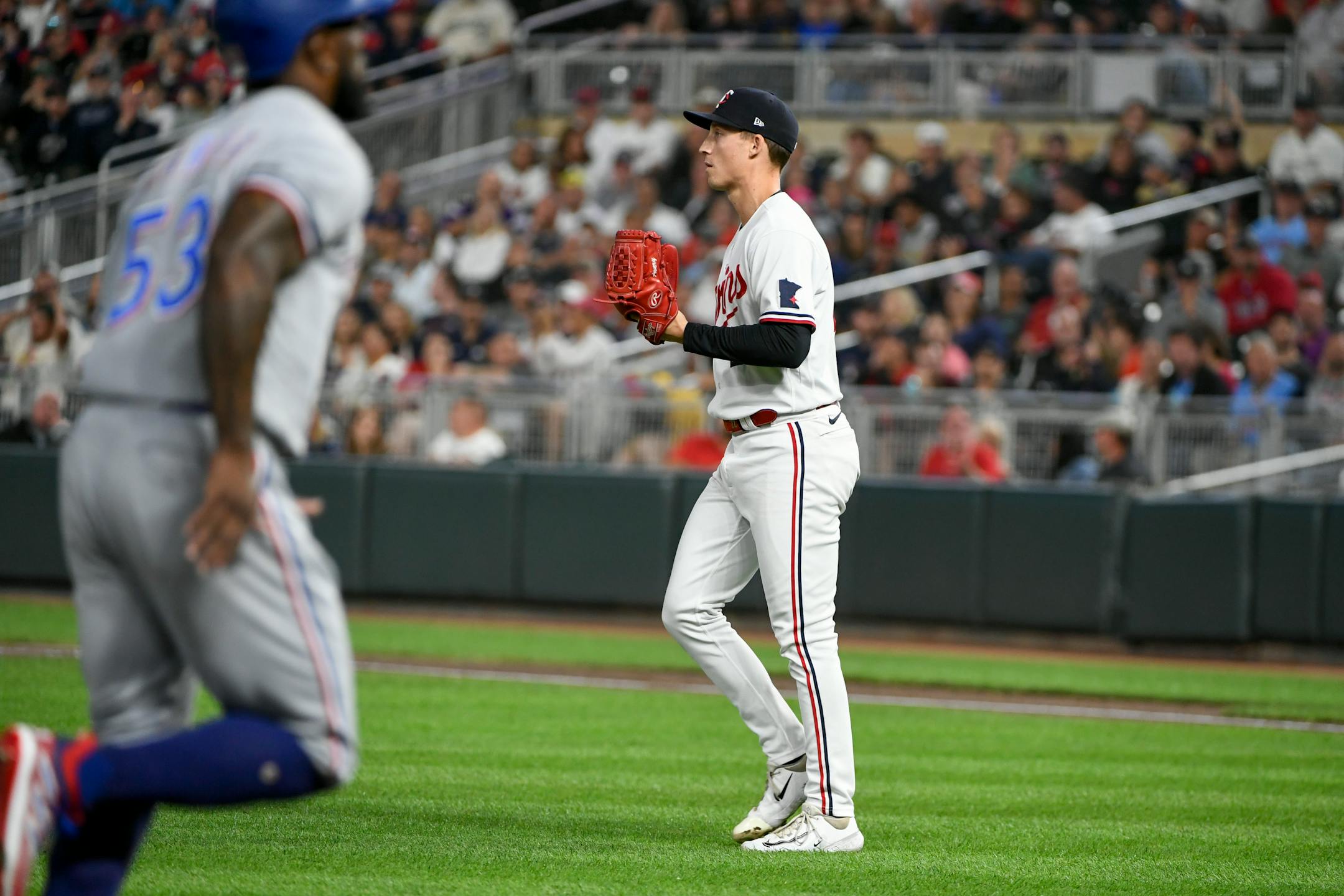 Minnesota Twins pitcher Griffin Jax, right, walks back to the mound as Texas Rangers' Adolis Garcia scores after walking Robbie Grossman during the ninth inning of a baseball game, Saturday, Aug. 26, 2023, in Minneapolis. (AP Photo/Craig Lassig)