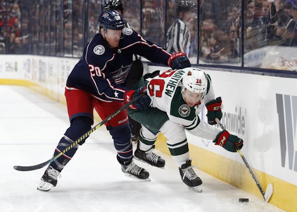 Columbus Blue Jackets forward Riley Nash, left, checks Minnesota Wild forward Gerald Mayhew during the first period of an NHL hockey game in Columbus,