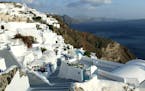 A couple take pictures in the village of Oia, on the cliffs of the island of Santorini, Greece, on Sept. 21, 2007. The troubled economy in Greece make