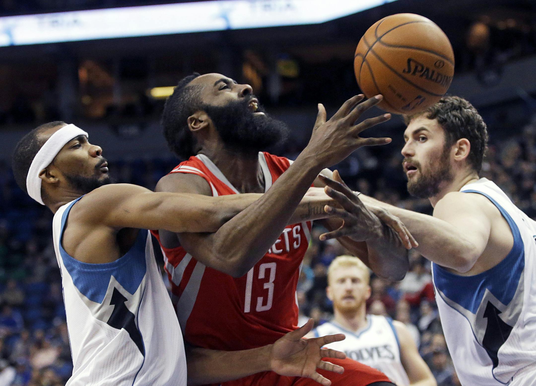 Houston Rockets' James Harden, center, is fouled by Minnesota Timberwolves' Corey Brewer, left, as Kevin Love also thwarts a scoring attempt in the second half of an NBA basketball game, Monday, Feb. 10, 2014, in Minneapolis. Harden scored 19 points. The Rockets won 107-89. (AP Photo/Jim Mone)
