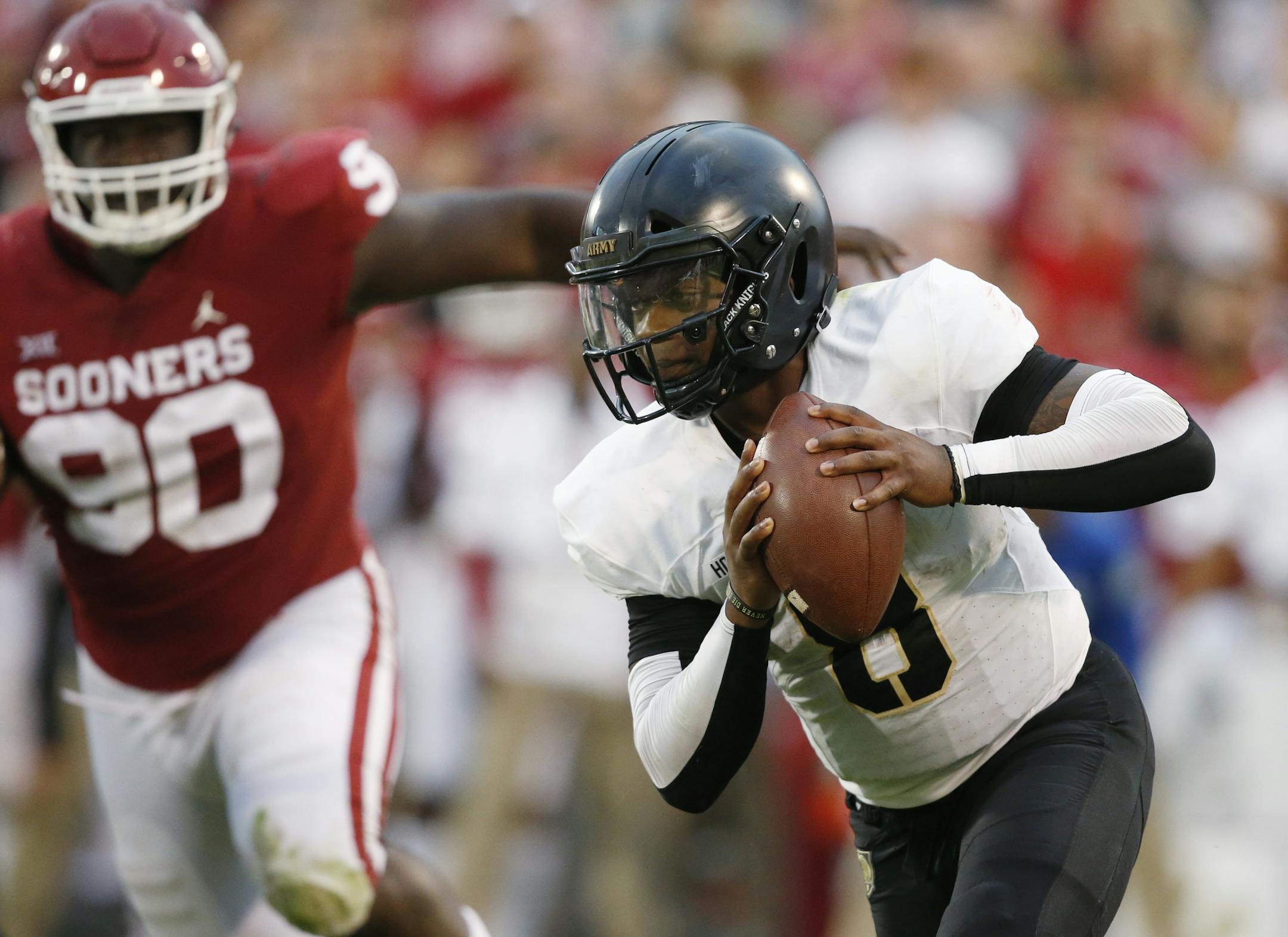 FILE - In this Sept. 22, 2018, file photo, Army quarterback Kelvin Hopkins Jr. (8) carries past Oklahoma defensive lineman Neville Gallimore (90) in the first of an NCAA college football game, in Norman, Okla. A year ago quarterback Hopkin knew he wasnít going to see much playing time under center for Army because starter Ahmad Bradshaw was having a stellar senior season for the Black Knights. Now, Hopkins is the lead man and has the demeanor he needs. (AP Photo/Sue Ogrocki, File)
