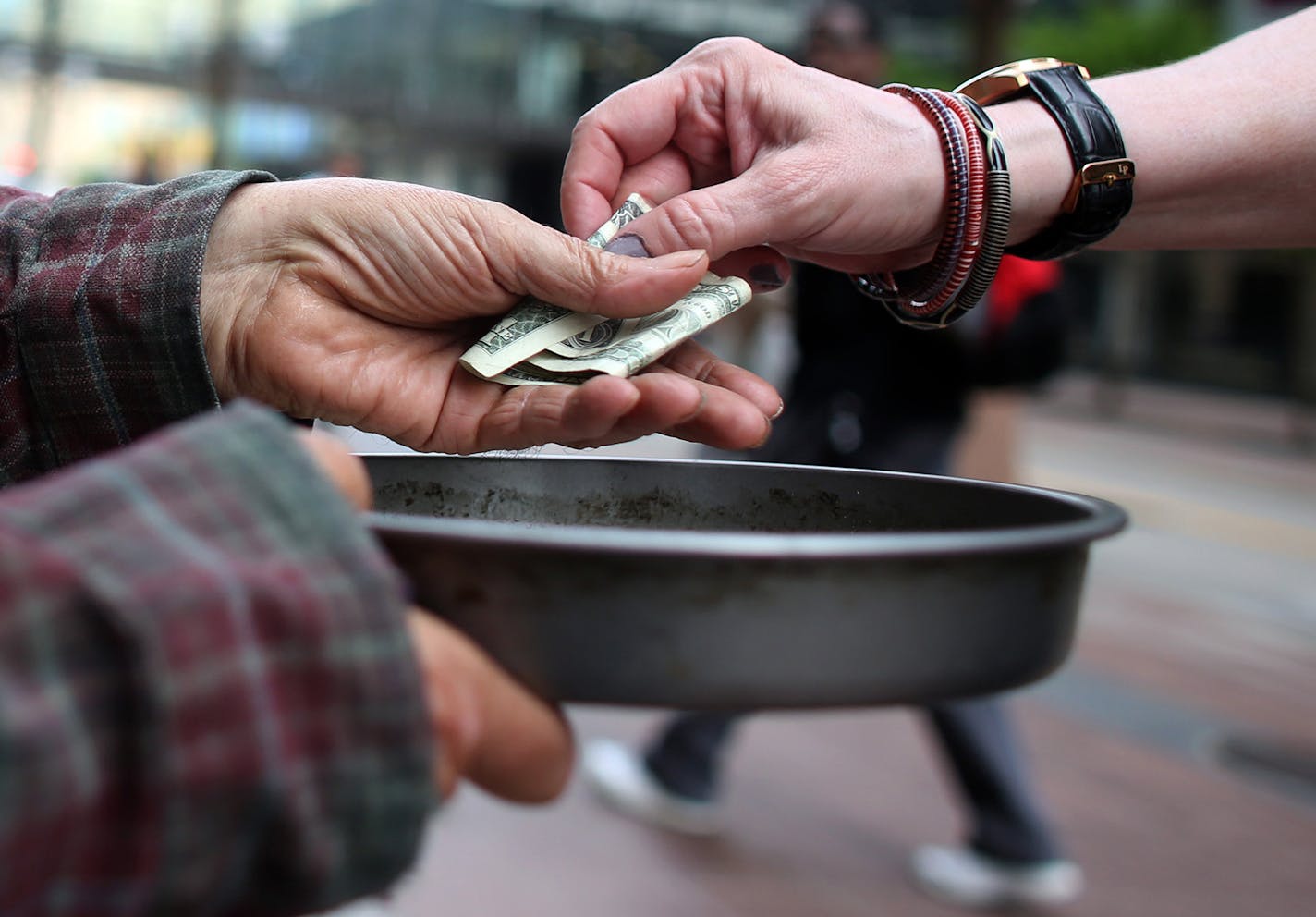 Edwin Schall got a dollar from a passerby as he held out a pan t get money for food along Nicollet Ave. ] (KYNDELL HARKNESS/STAR TRIBUNE) kyndell.harkness@startribune.com In downtown Minneapolis, Min. Tuesday, June 3, 2014. A new campaign in Minneapolis wants to end panhandling. The "Give Real Change Campaign" which has billboards in Downtown Minneapolis, is telling residents to end panhandling and give to a charitable organization instead. ORG XMIT: MIN1406031618130714