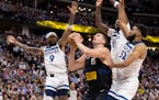Nikola Jokic (25) of the Denver Nuggets is defended by Nickeil Alexander-Walker (9), Naz Reid (11), and Karl Anthony Towns (32) of the Timberwolves in