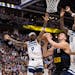 Nikola Jokic of the Nuggets is surrounded by Wolves players Nickeil Alexander-Walker (9), Naz Reid (11), and Karl Anthony Towns on Monday night in Den