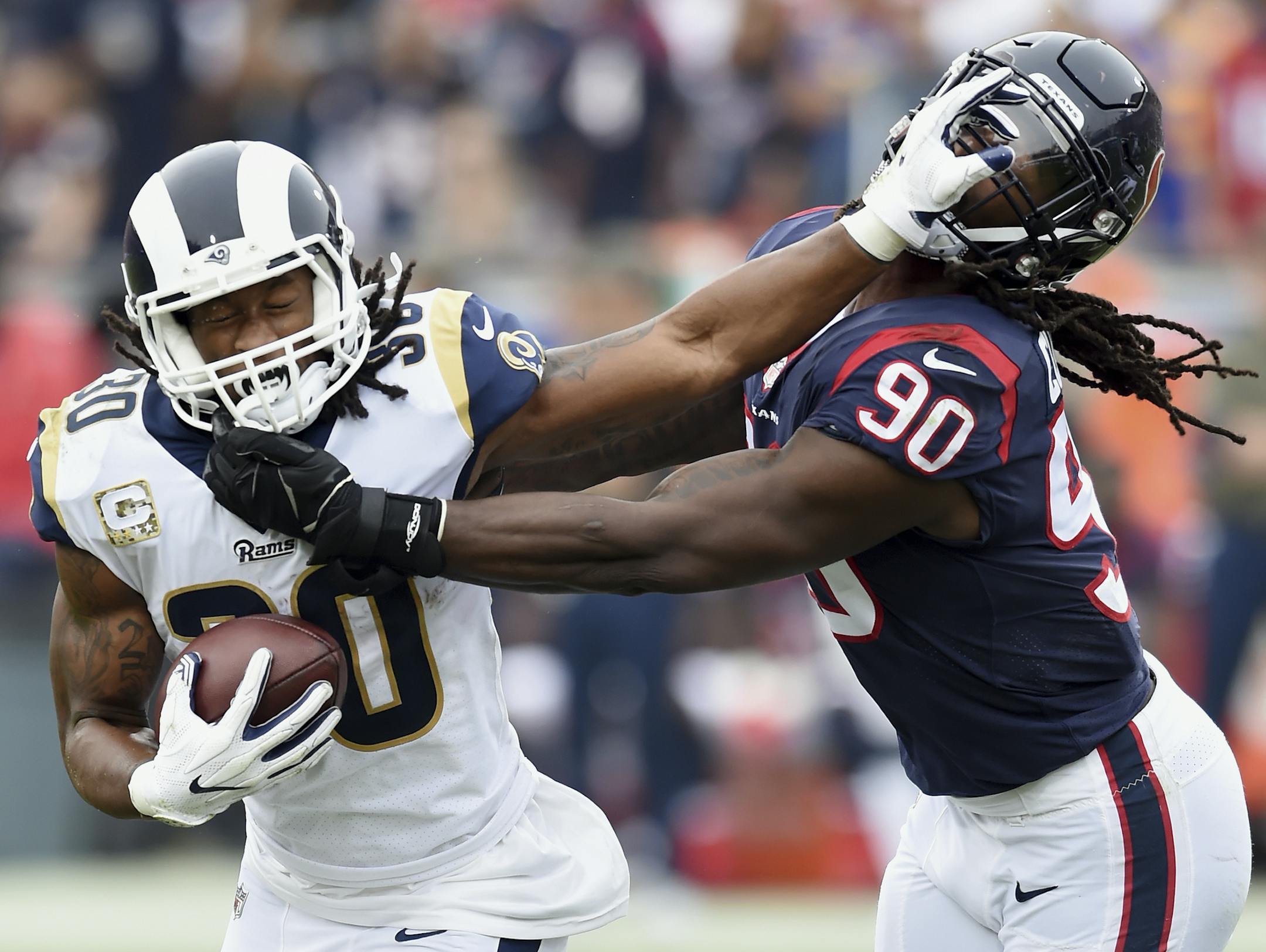 Los Angeles Rams running back Todd Gurley II (30) straight arms Houston Texans linebacker/defensive end Jadeveon Clowney (90) during a running play in the second quarter of a game played at the Los Angeles Memorial Coliseum in Los Angeles on Sunday, November 12, 2017. (AP Photo/John Cordes)