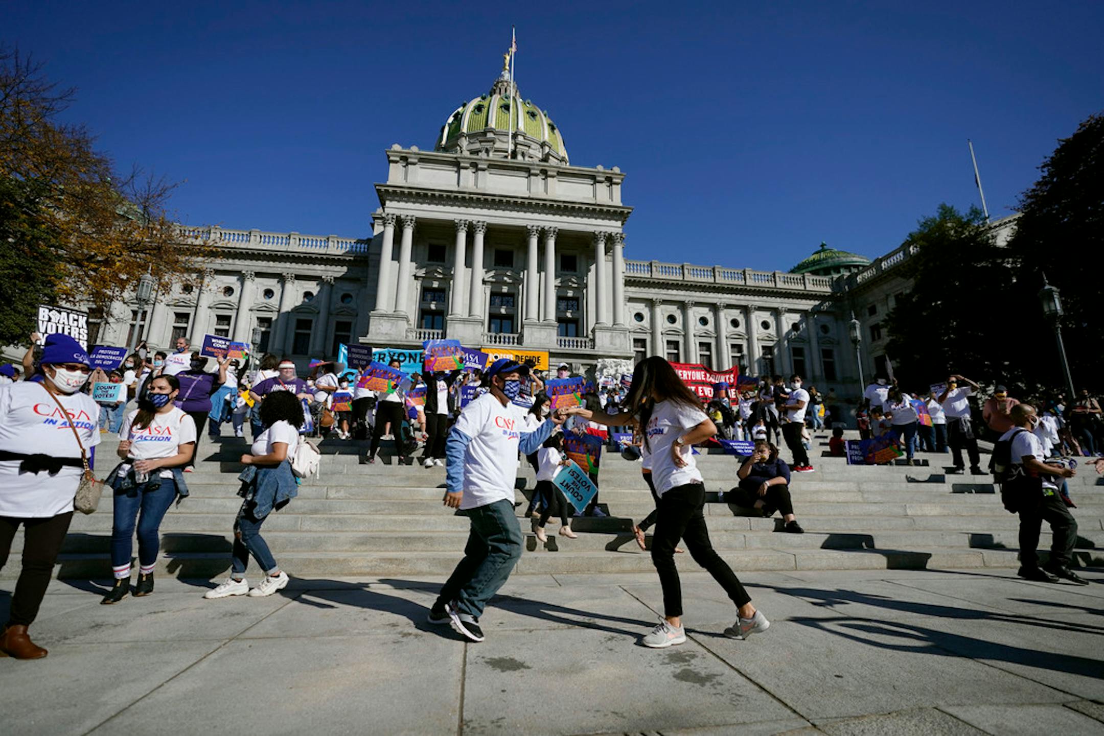 People dance in celebration outside the Pennsylvania State Capitol, Saturday, Nov. 7, 2020, in Harrisburg, Pa., after Democrat Joe Biden defeated President Donald Trump to become 46th president of the United States. (AP Photo/Julio Cortez)