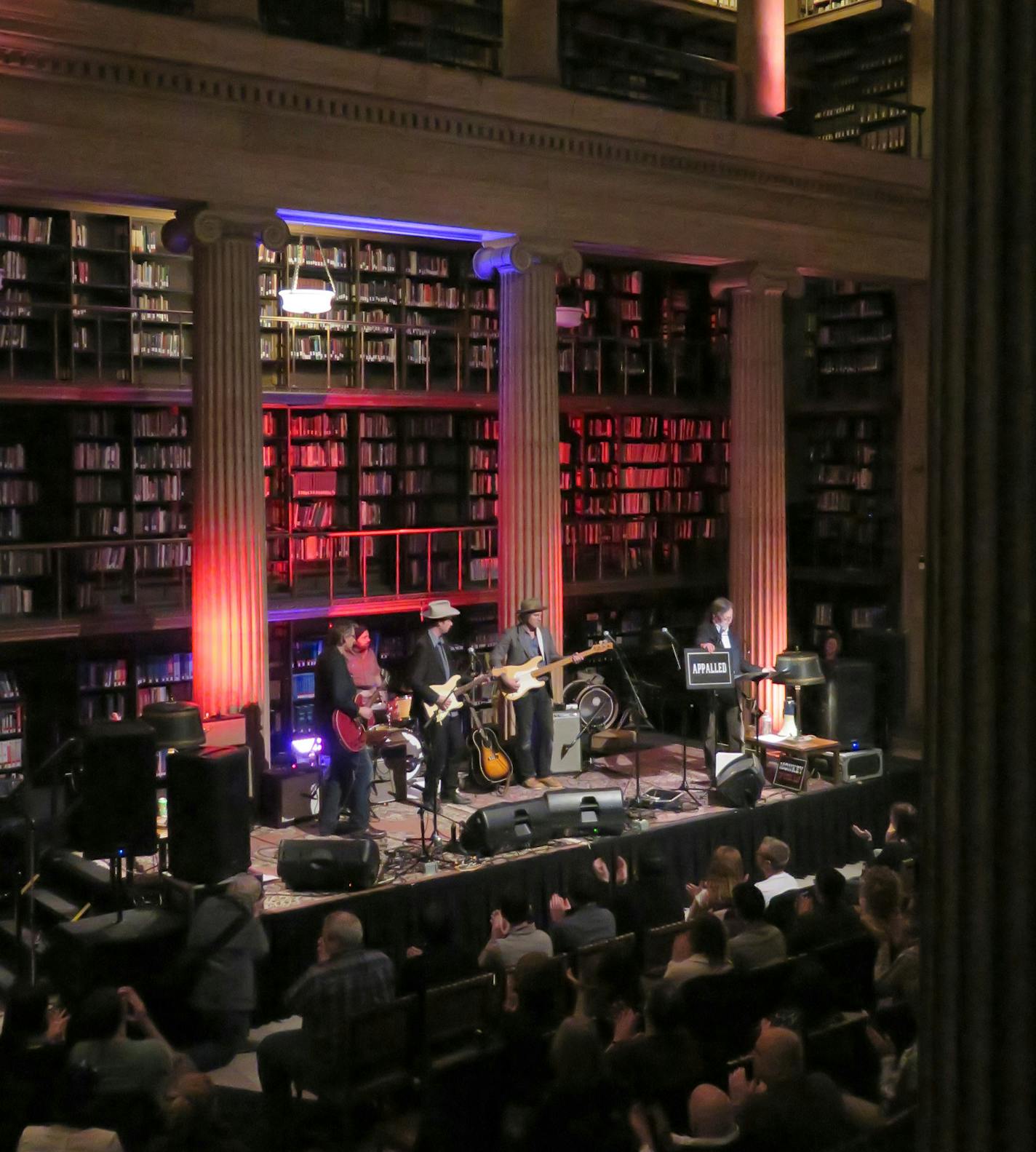 Best of MN - Real Phonic Radio Hour - live performances of Americana themed music monthly at the James J. Hill Reference Library in downtown St. Paul. On stage the 'house band' led by Erik Koskinen ( white hat ) and host Thom Middelbrook, - displaying the "appalled ' (sic) sign.