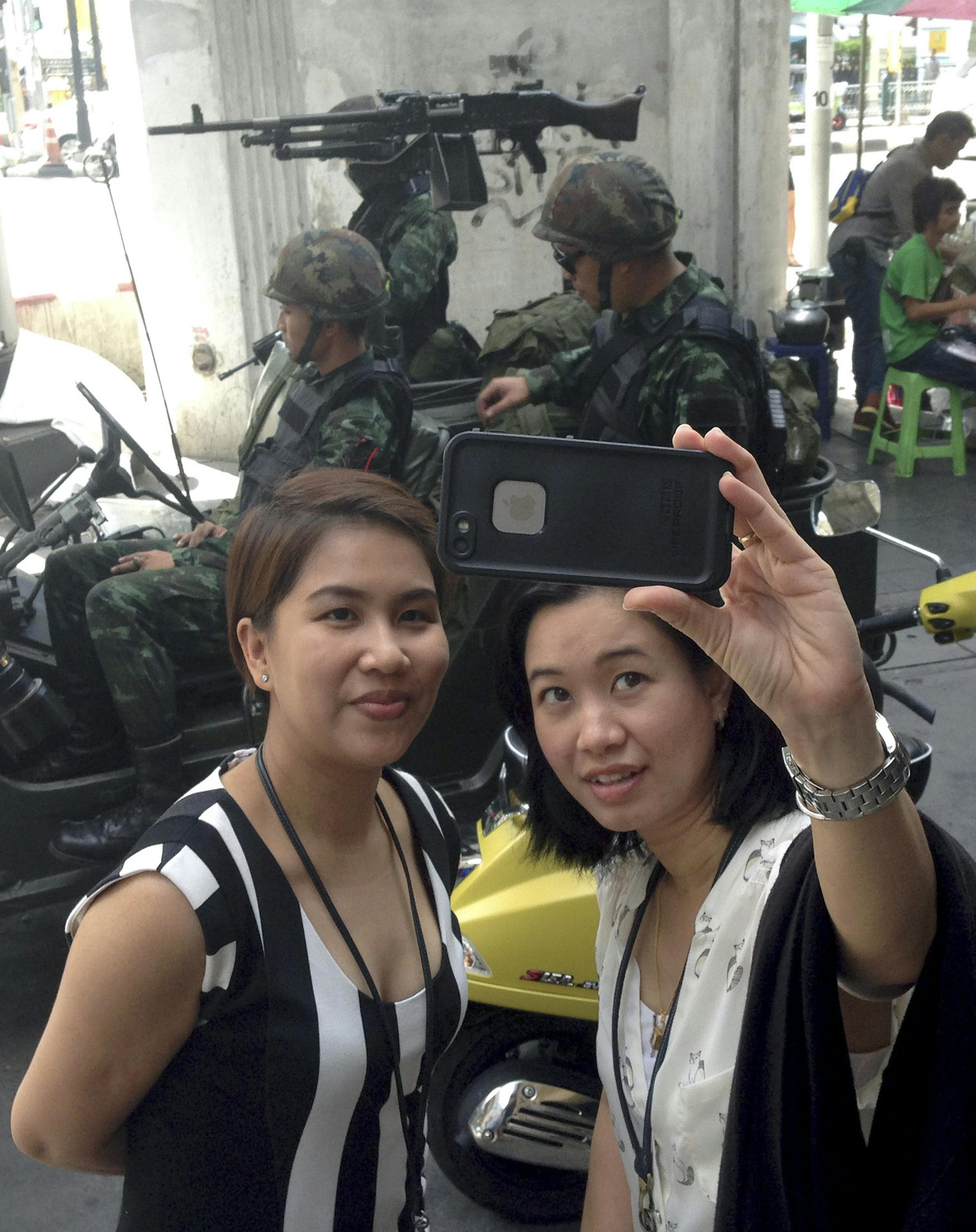 Residents stop to take a photograph of themselves at a military checkpoint in central Bangkok, Thailand, Tuesday, May 20, 2014. Thailand's army declared martial law in a surprise announcement before dawn Tuesday that it said was aimed at keeping the country stable after six months of sometimes violent political unrest. The military, however, denied a coup d'etat was underway. (AP Photo/Kiko Rosario)