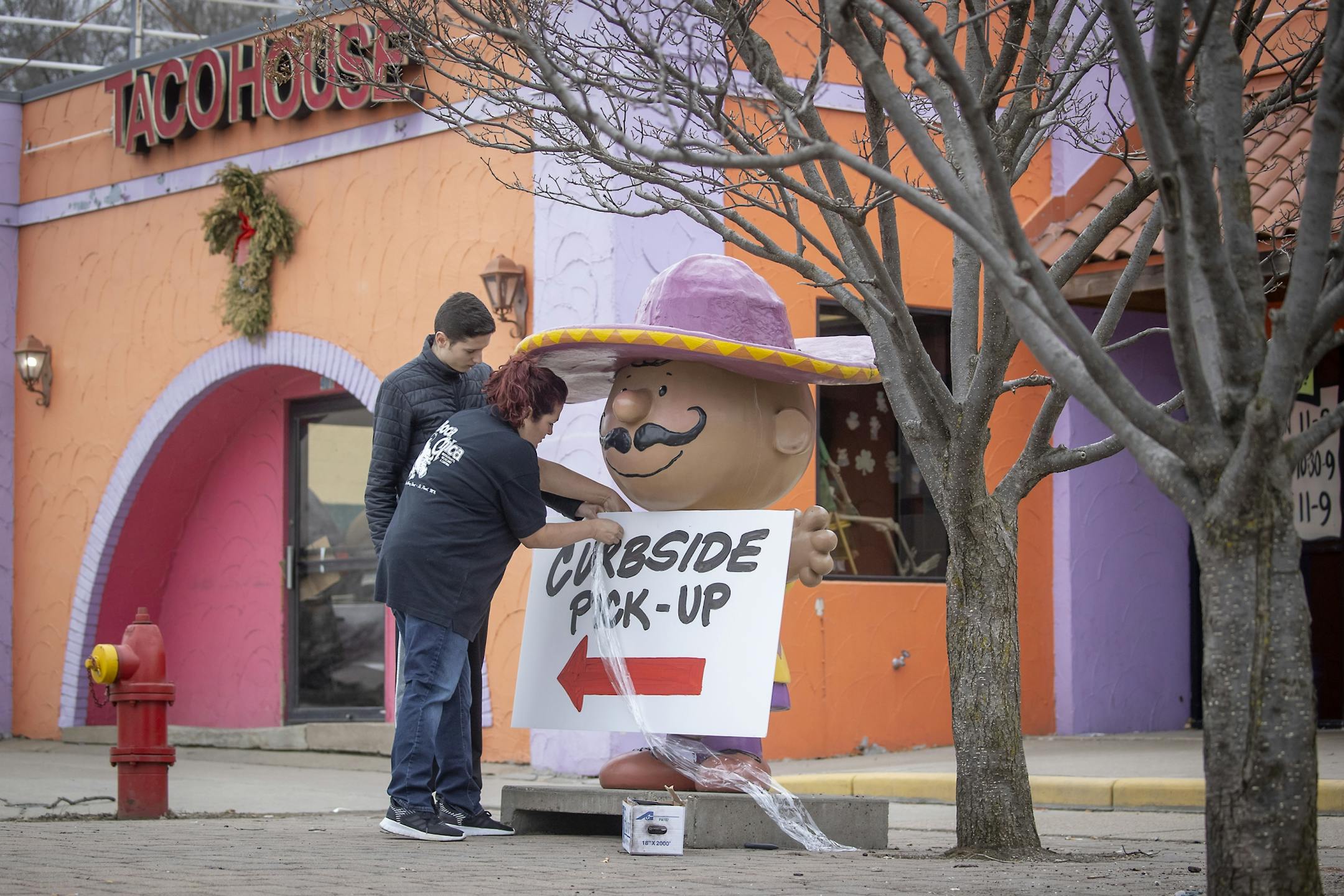 Miguel Frias, left, and Jenny Frias placed a sign outside Taco House, to notify clients that they moved from dine-in/take-out to curb-side, Wednesday, March 18, 2020 in St. Paul, MN.