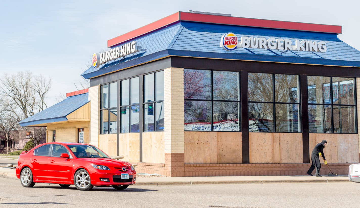 A man sweeps bits of broken glass that is now replaced by boards, the Burger King remains open. ] Elizabeth Brumley special to the Star Tribune * A prank caller Friday night convinced the manager of a Coon Rapids Burger King to have employees smash out all the windows to keep the building from blowing up