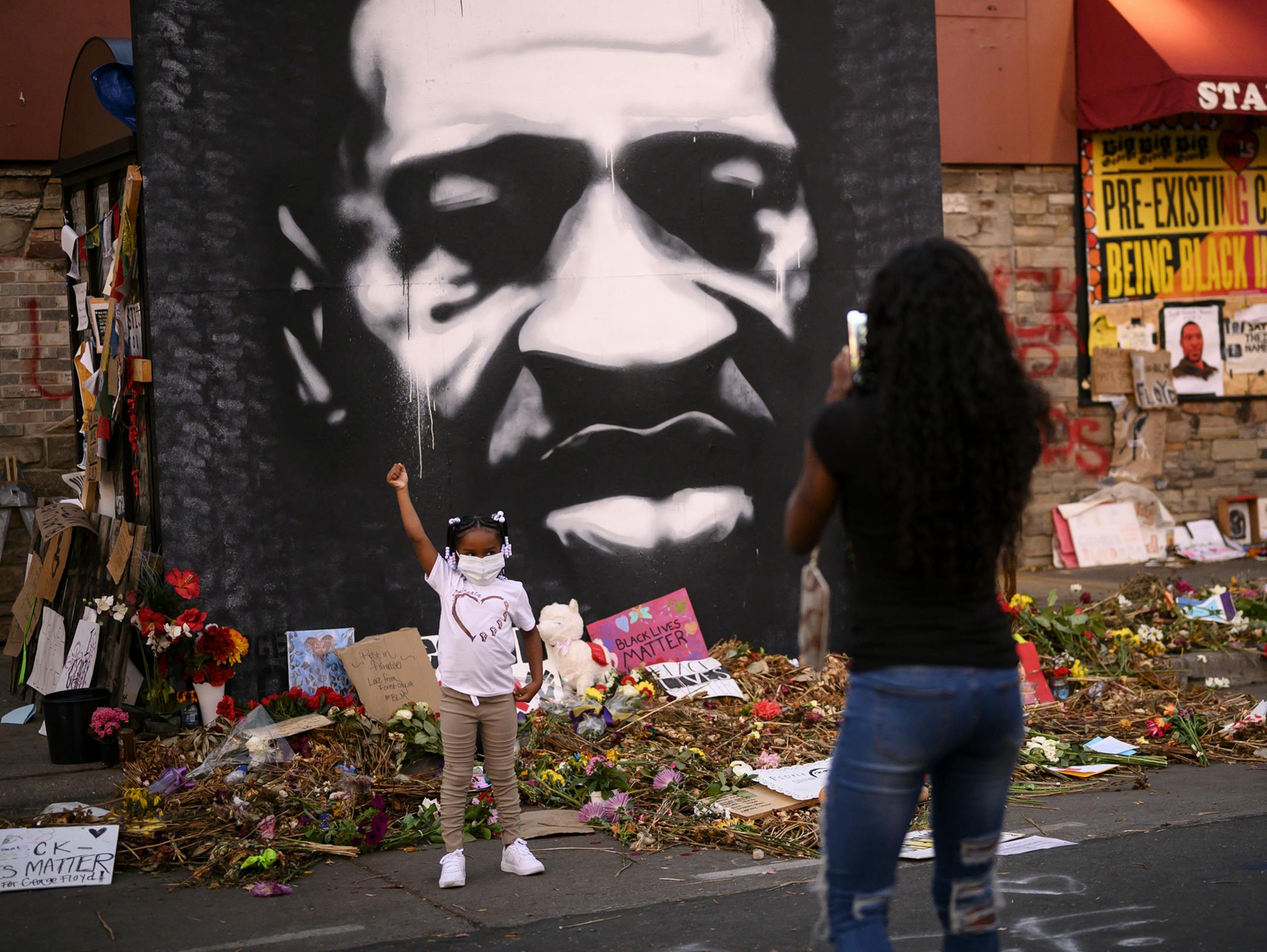 A child raised her fist in the air for a photo at George Floyd's memorial outside Cup Foods. ] aaron.lavinsky@startribune.com The scene outside Cup Foods in Minneapolis, as Juneteenth was celebrated near the site where George Floyd was killed at the hands of Minneapolis Police in late May.