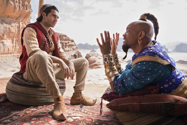 This image released by Disney shows Mena Massoud as Aladdin, left, and Will Smith as Genie in Disney's live-action adaptation of the 1992 animated cla