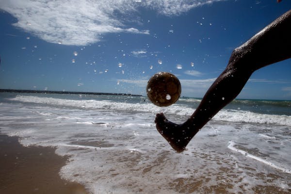 A man kicks a soccer ball on the shores of Beira Mar, in Fortaleza, Brazil, Tuesday, June 10, 2014. Soccer fans around the world are gearing up to wat