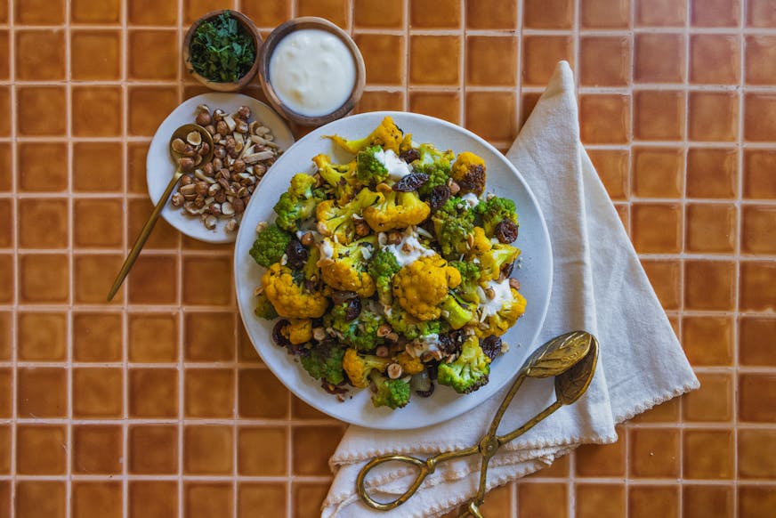 A bowl of golden "cheddar" cauliflower and dark green Romanesco with dried cranberries, vinegar, honey and nuts.