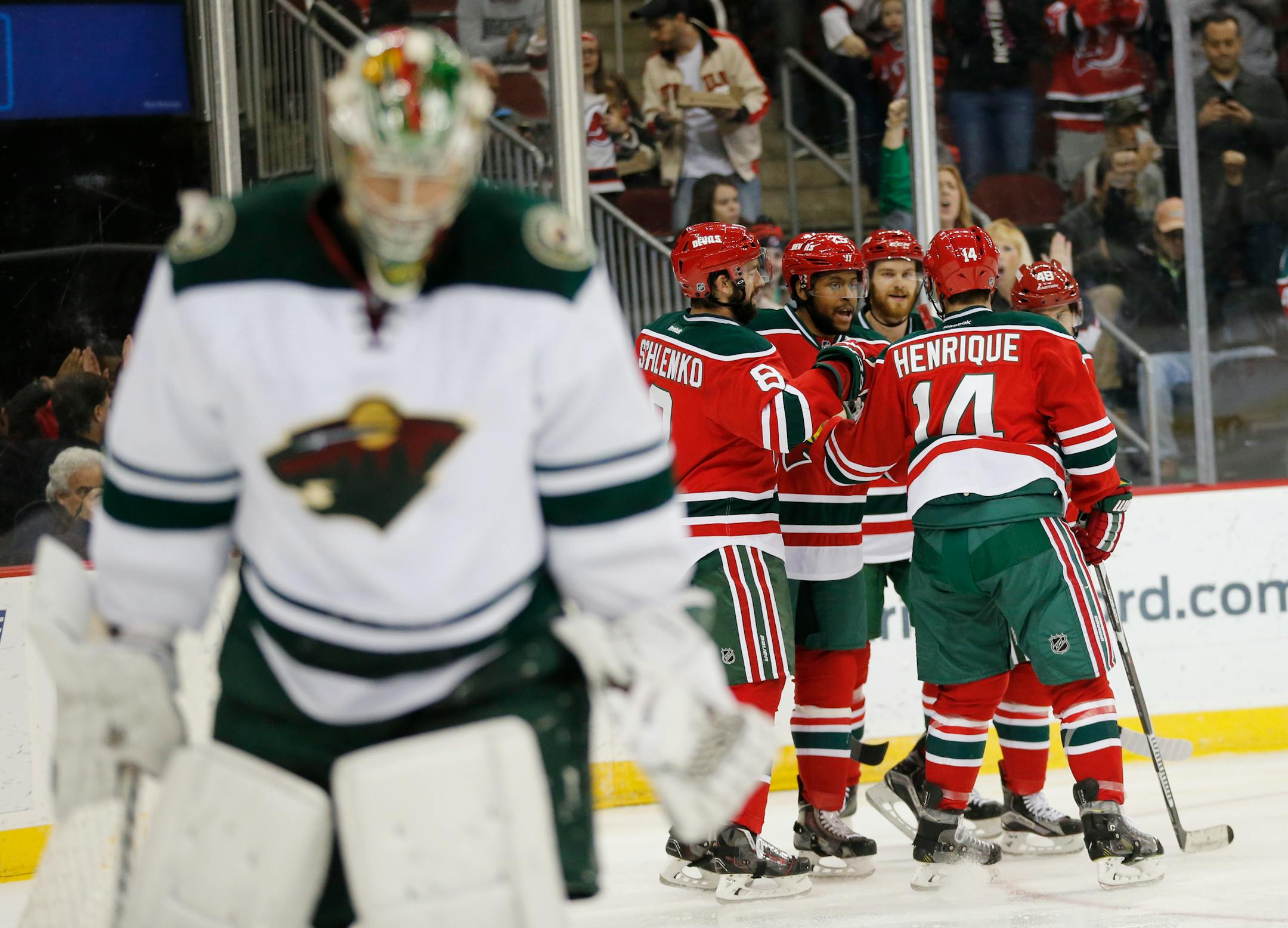 New Jersey Devils players celebrate a goal by Devante Smith-Pelly, center left, as Minnesota Wild goalie Darcy Kuemper skates away during the second period of an NHL hockey game, Thursday, March 17, 2016, in Newark, N.J. (AP Photo/Julio Cortez)