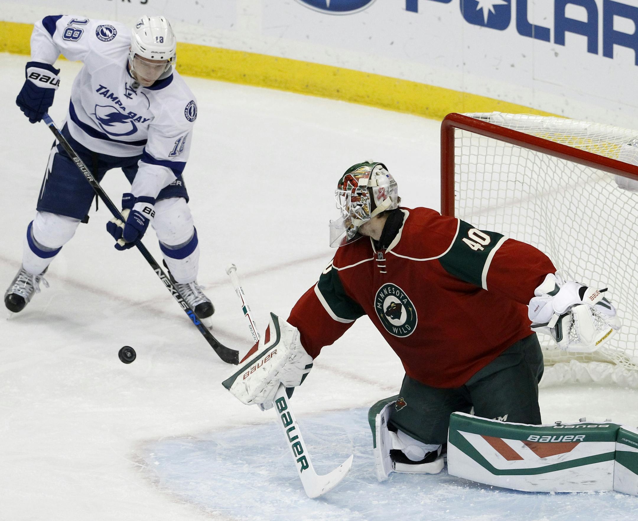 Minnesota Wild goalie Devan Dubnyk (40) deflects a shot in front of Tampa Bay Lightning left wing Ondrej Palat (18), of the Czech Republic, during the first period of an NHL hockey game in St. Paul, Minn., Saturday, Nov. 7, 2015. (AP Photo/Ann Heisenfelt)