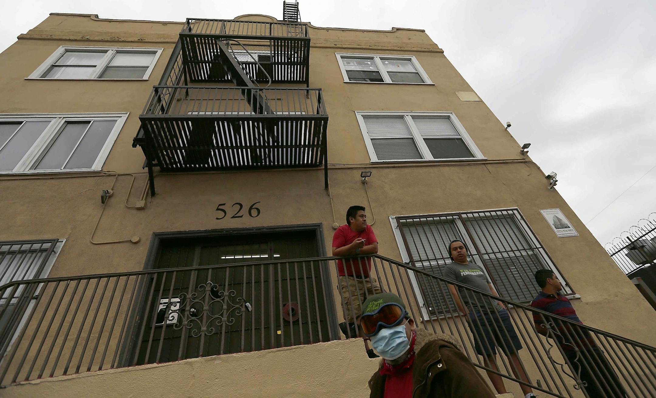 Men stand outside an apartment building in the Westlake District of Los Angeles, which has the second highest population density in the city, with about 38,214 people per square mile.