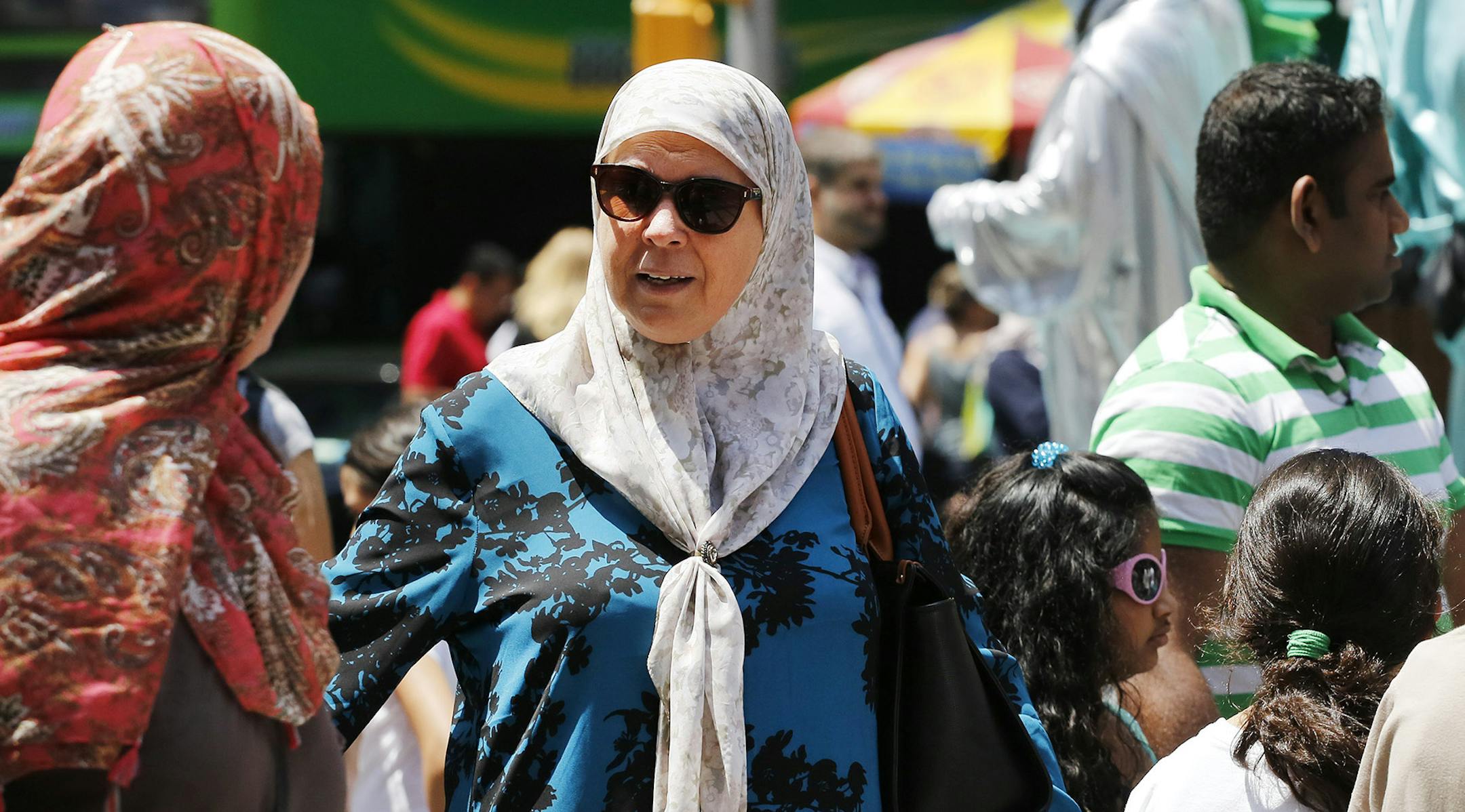 Muslim women walk past Statue of Liberty characters, Sunday, July 17, 2016, in New York's Times Square. (AP Photo/Mark Lennihan) ORG XMIT: OTKNYML106
