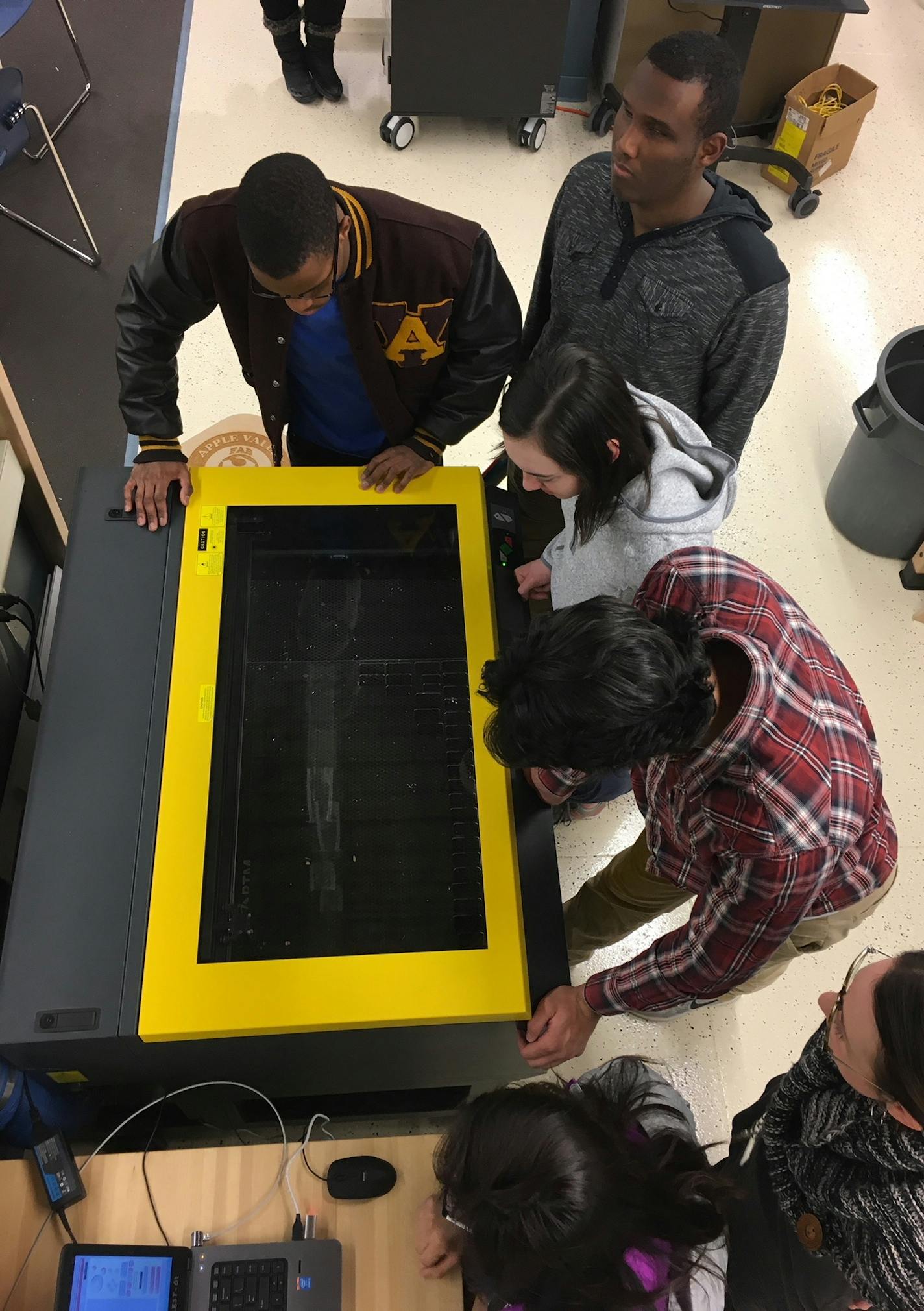 Apple Valley High School students work in groups on the laser engraver in the "Fab Lab" to create a prototype for BTM Global.