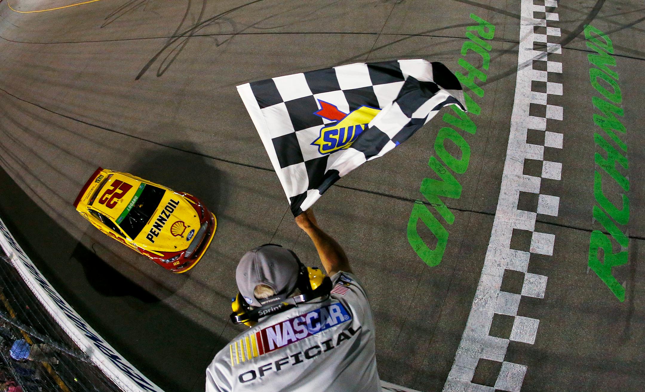 In a photo provided by NASCAR, Joey Logano takes the checkered flag to win the NASCAR Sprint Cup Series auto race at Richmond International Raceway on Saturday, April 26, 2014, in Richmond, Va. (AP Photo/NASCAR, Jeff Zelevansky)