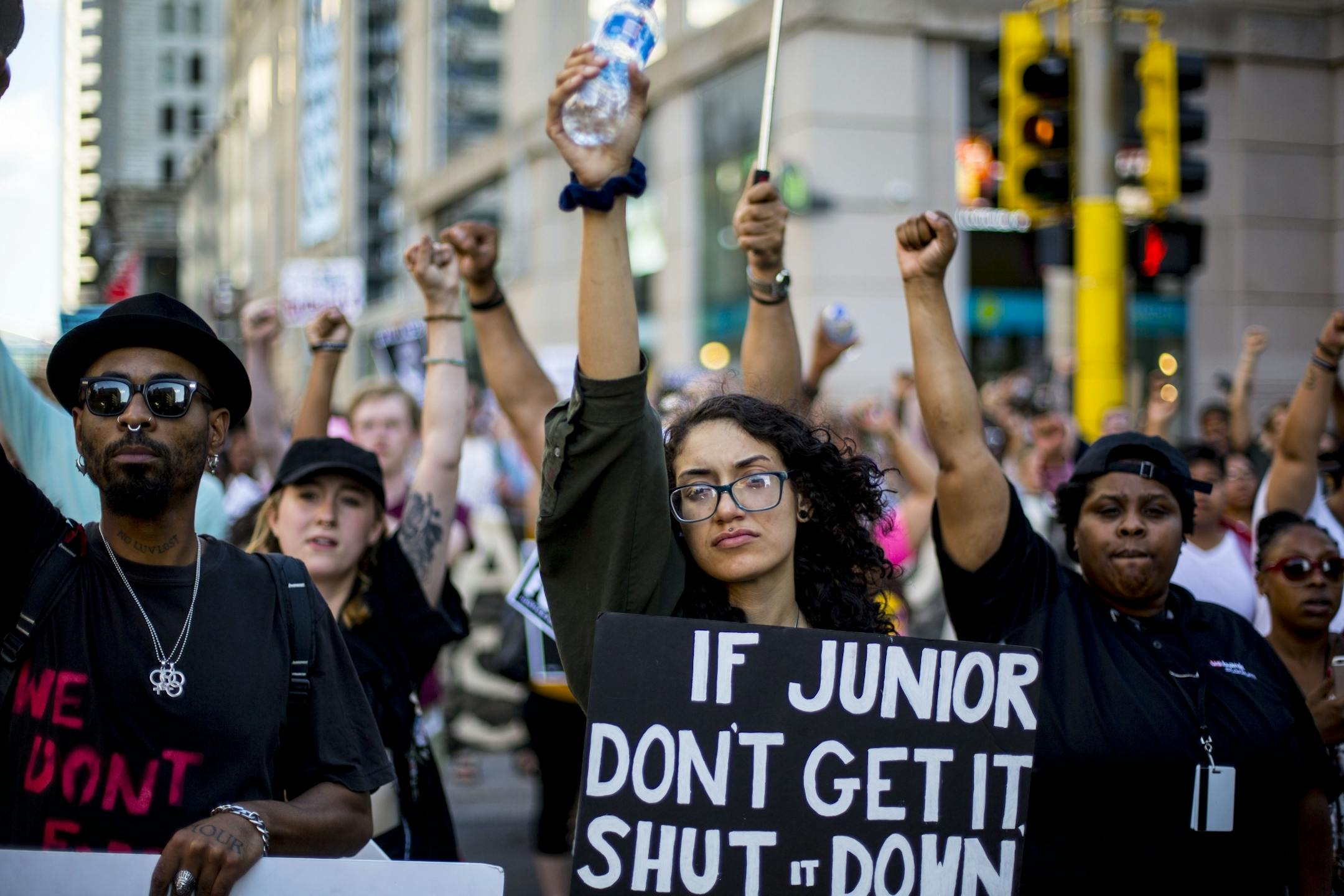 Protestors raise their fists in solidarity as they block of an intersection.
