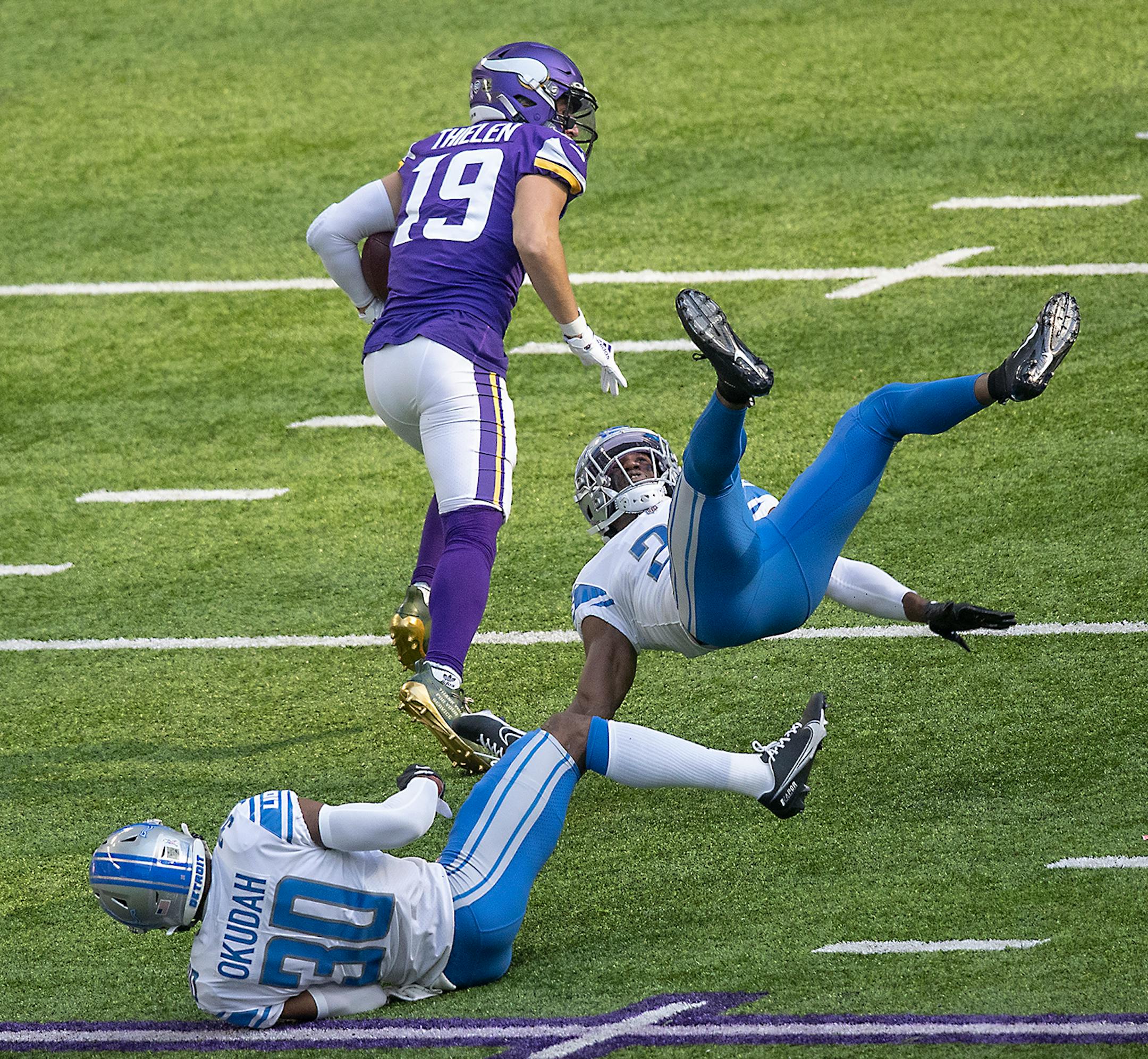 Minnesota Vikings wide receiver Adam Thielen made a grab for a first down despite defensive coverage from Detroit Lions cornerback Jeff Okudah, left, and Detroit Lions strong safety Duron Harmon in the first quarter.