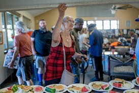 Kay Countryman opens the kitchen awning as lunch is served to a packed dining area at Peace House, a homeless drop in center in Minneapolis on June 26