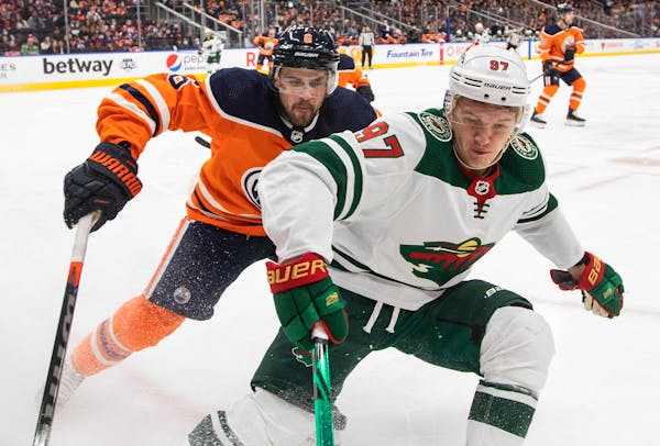 Minnesota Wild's Kirill Kaprizov (97) and Edmonton Oilers' Kris Russell (6) vie for the puck during the first period of an NHL hockey game Tuesday, De