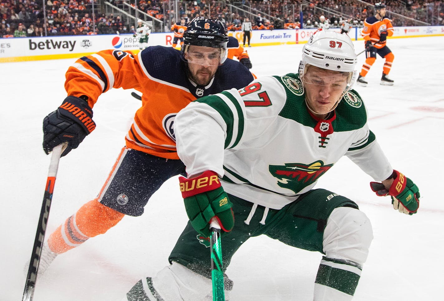 Minnesota Wild's Kirill Kaprizov (97) and Edmonton Oilers' Kris Russell (6) vie for the puck during the first period of an NHL hockey game Tuesday, Dec. 7, 2021, in Edmonton, Alberta. (Jason Franson/The Canadian Press via AP)