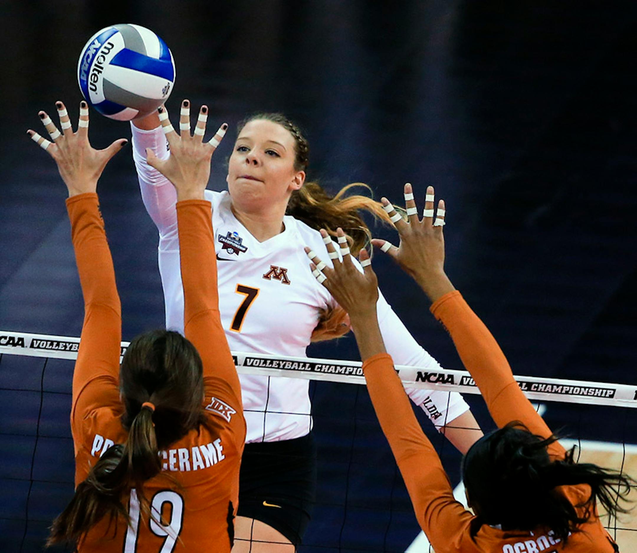 Minnesota's Hannah Tapp (7) spikes the ball against Texas' Paulina Prieto Cerame (19) and Chiaka Ogbogu (11) during an NCAA women's volleyball tournament semifinal in Omaha, Neb., Thursday, Dec. 17, 2015.