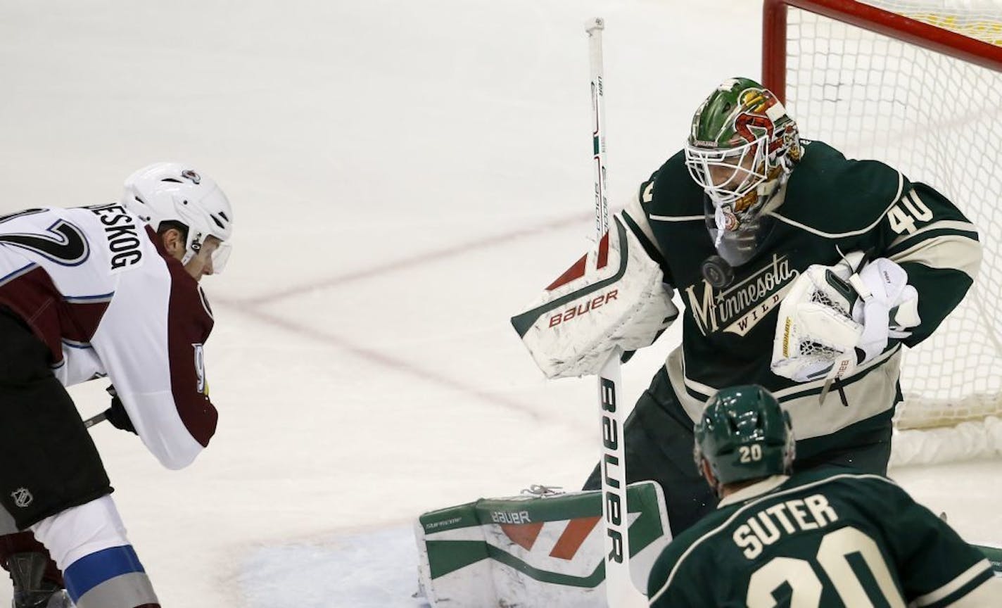 Minnesota Wild goalie Devan Dubnyk (40) deflects a shot by Colorado Avalanche left wing Gabriel Landeskog, left, of Sweden, during the first period of an NHL hockey game in St. Paul, Minn., Saturday, Dec. 5, 2015.