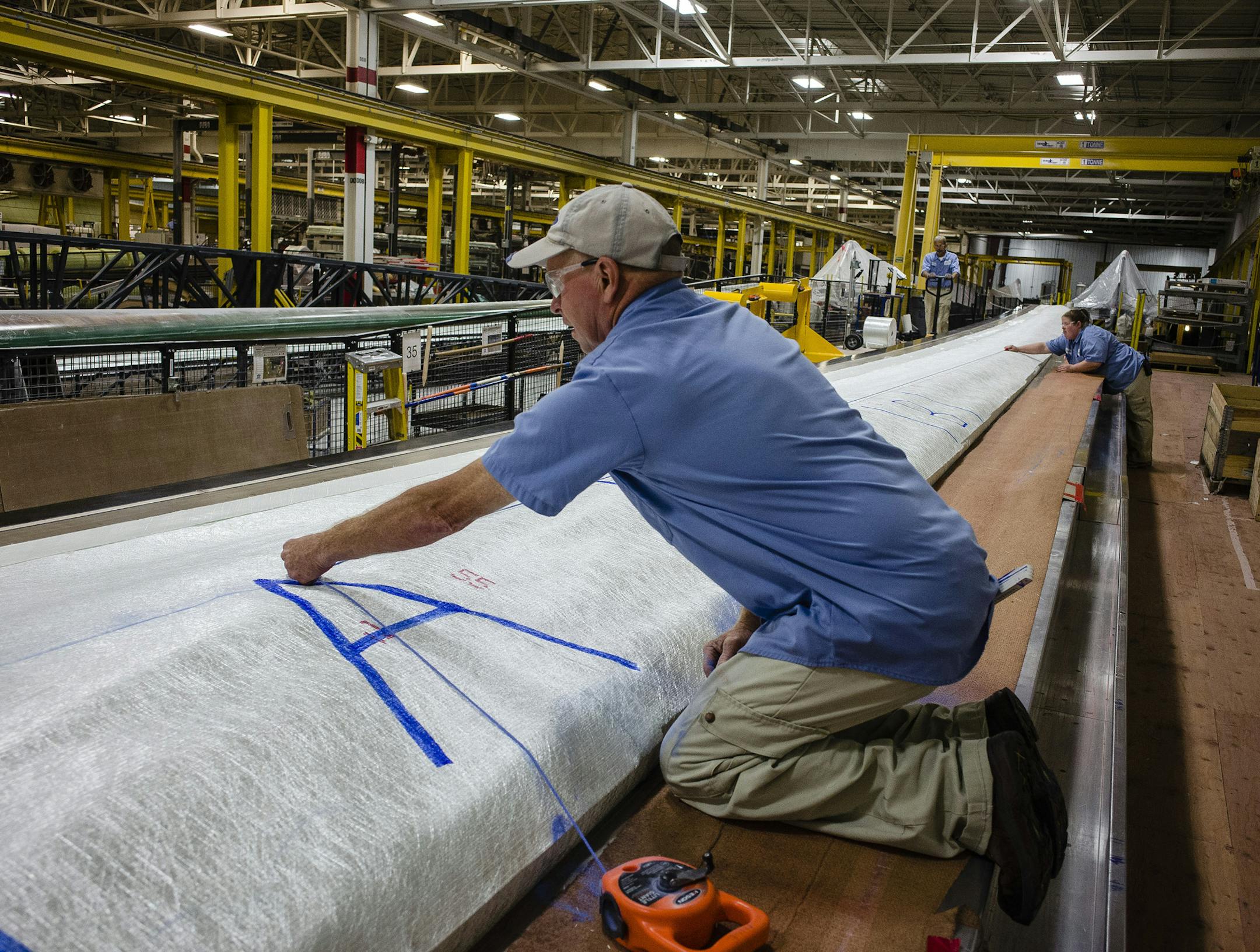 Workers snap a chalk line onto a wind turbine blade prior to baking during the final stages of production at the Siemens AG turbine blade plant in Fort Madison, Iowa, U.S., on Wednesday, Aug. 20, 2014. The U.S. Export-Import Bank agreed to lend $65 million for Peruvian wind farms that will use Siemens AG turbines made in Fort Madison and at another Siemens plant in Kansas. Photographer: Timothy Fadek/Bloomberg ORG XMIT: 509474689