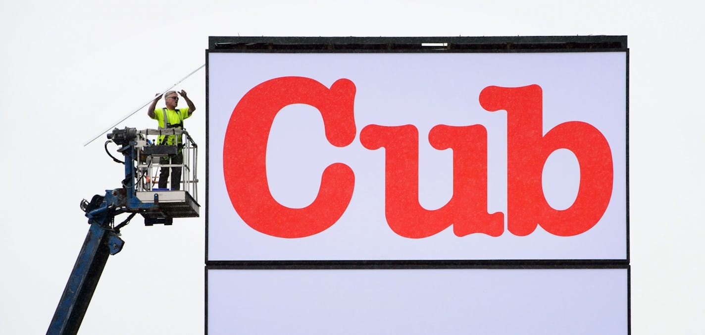 A worker puts finishing touches on the Cub Foods sign directly across the street from Hy-Vee.