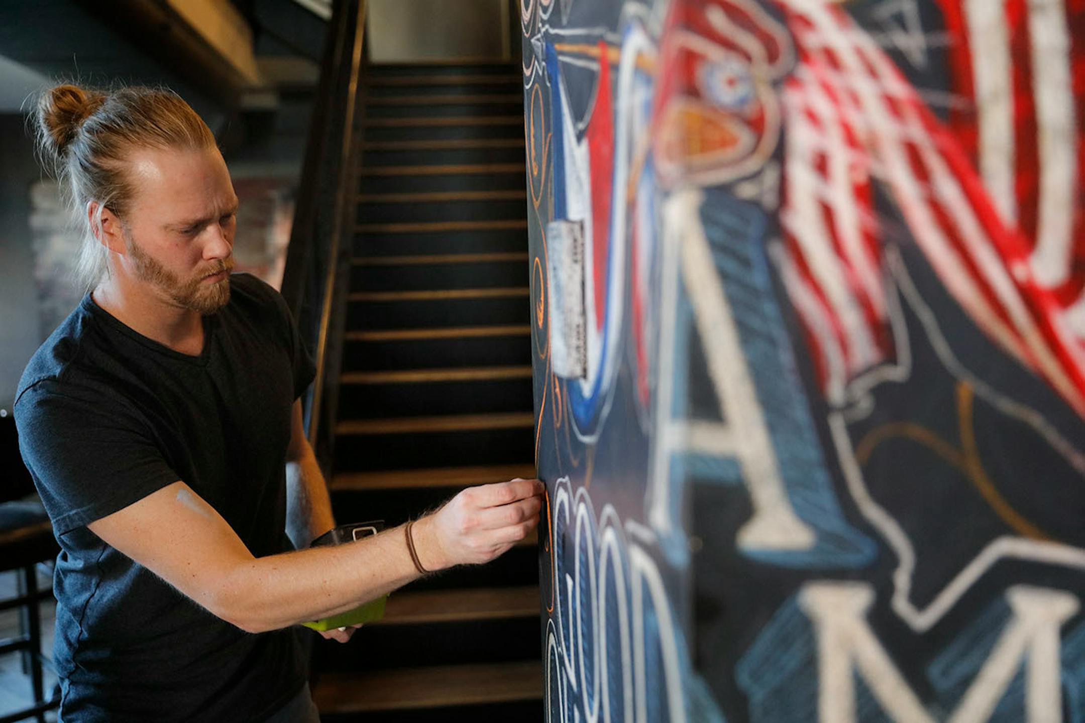 Adam Dennis works on his murals at Coup d'Etat restaurant in Uptown. Dennis' work include Smack Shack and the Pourhouse and is done with chalk and spray paint.