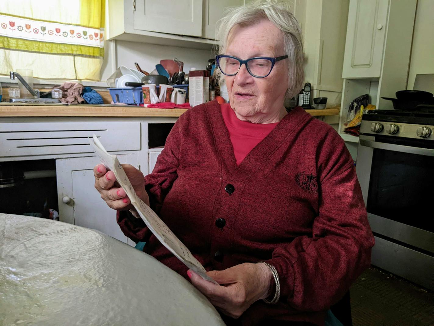 Joy Rindels-Hayden, seated in her kitchen in May 2023, read her bill that improves bus safety for Minnesotans with disabilities. Photo by Chris Serres