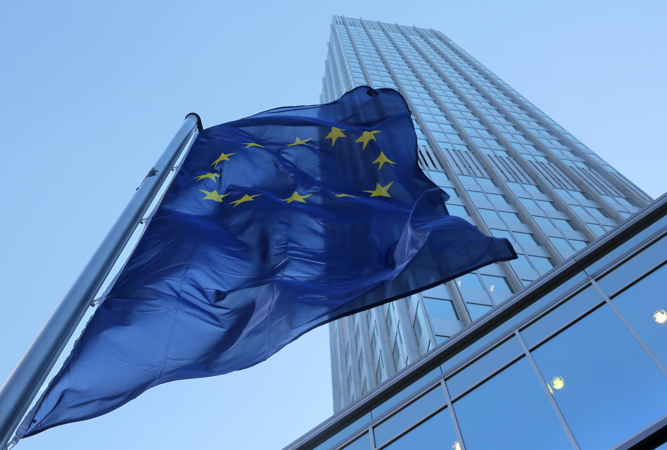 A European Union (EU) flag flies outside of the headquarters of the European Central Bank (ECB) in Frankfurt, Germany, on Wednesday, Aug. 1, 2012. As Denmark experiments with official interest rates below zero, European Central Bank President Mario Draghi is getting a glimpse of how extreme monetary policy decisions play out in real life. Photographer: Hannelore Foerster/Bloomberg
