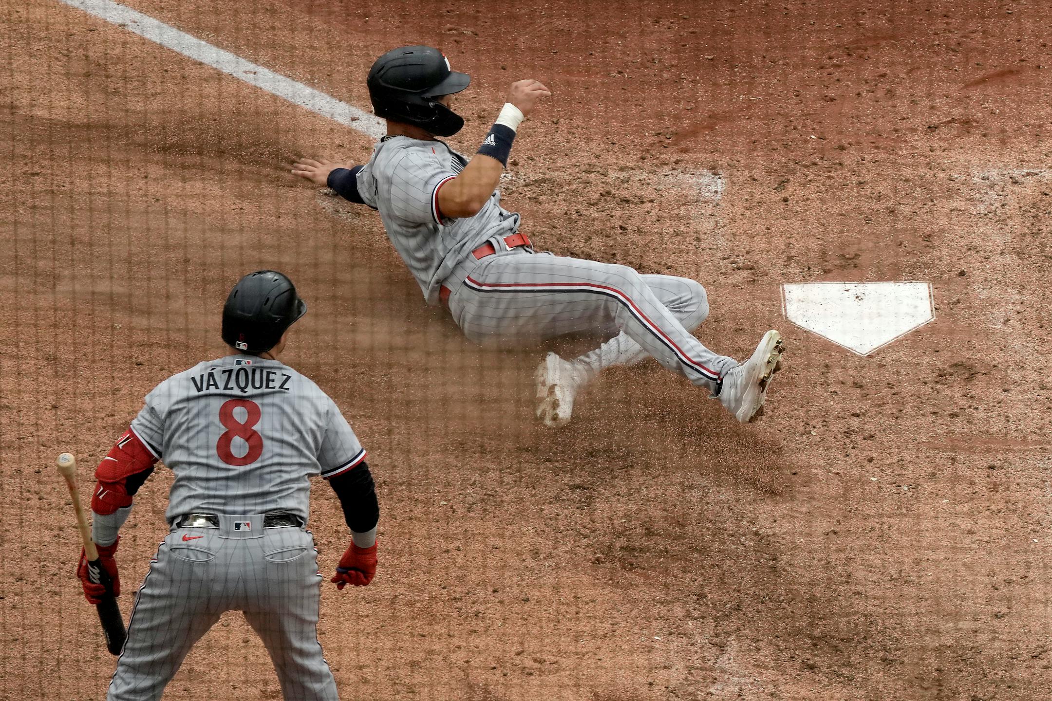 Minnesota Twins' Trevor Larnach slides home to score on an RBI single hit by Donovan Solano during the sixth inning of an opening day baseball game against the Kansas City Royals in Kansas City, Mo., Thursday, March 30, 2023. (AP Photo/Charlie Riedel)