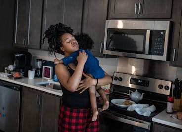 Imani Swinney gives one of her two daughters a hug as she made pancakes in their Minneapolis apartment on April 23.