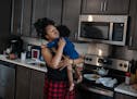 Imani Swinney gives one of her two daughters a hug as she made pancakes in their Minneapolis apartment on April 23.