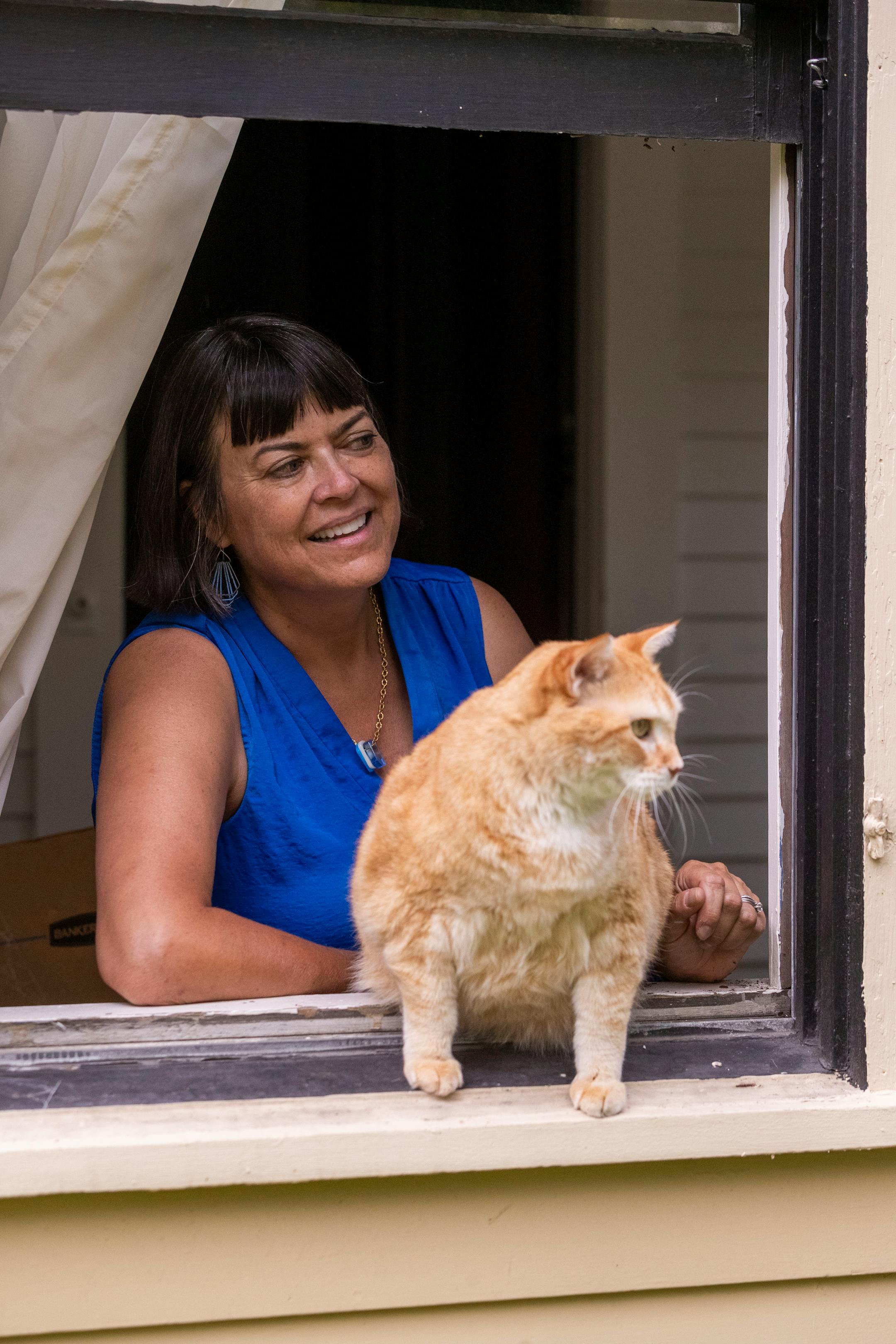 Nina Hale and her cat Rilke, a 14-year old orange tabby, look out the window on Thursday, July 29, 2021, in Minneapolis. Rilke will be one of the cats on the 5th annual Cat Tour at The Wedge on August 4th. ] ANTRANIK TAVITIAN • anto.tavitian@startribune.com