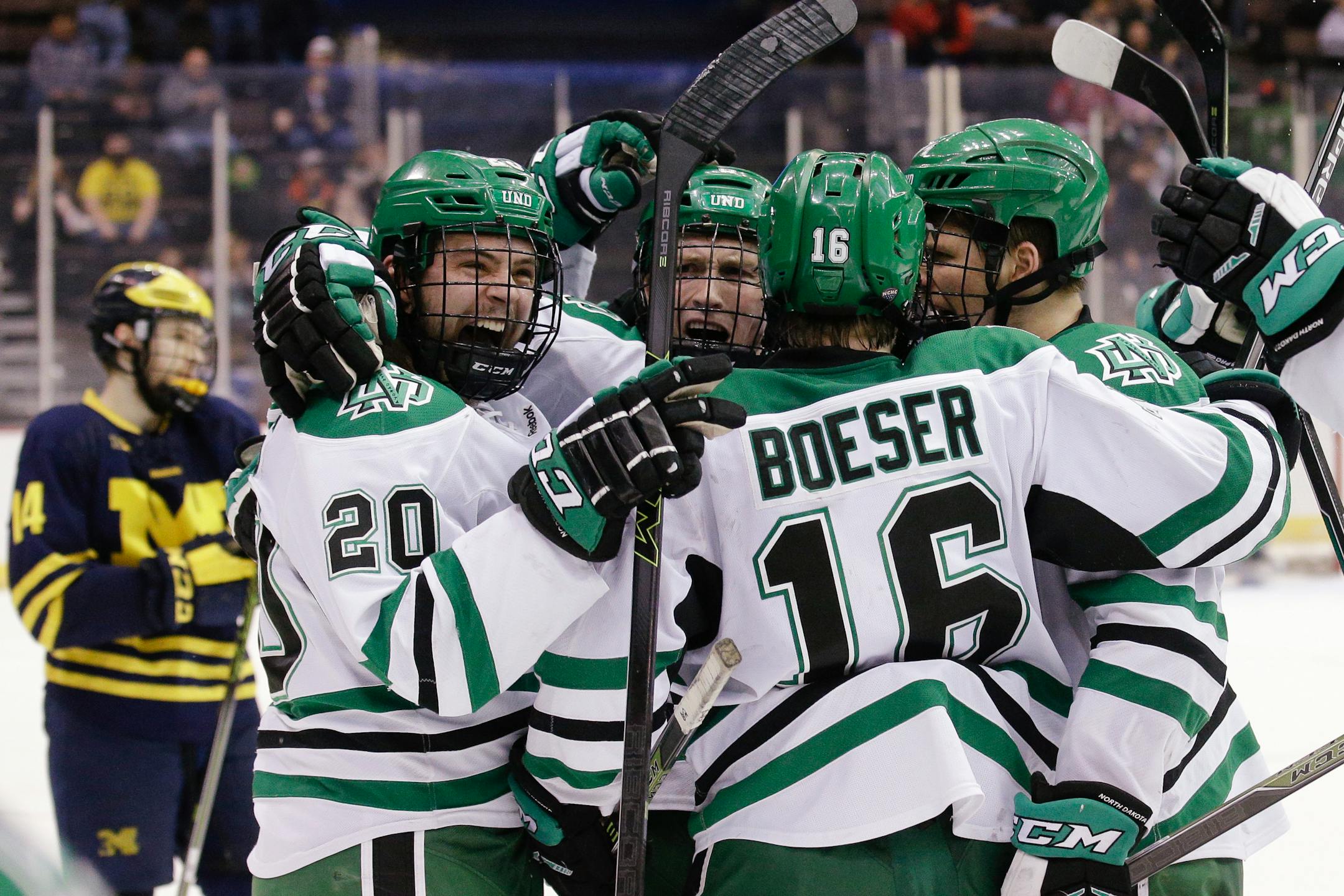 North Dakota's Paul LaDue, center, celebrates after scoring an empty-net goal against Michigan, with teammates Gage Ausmus (20) and Brock Boeser (16), during the third period of the Midwest Regional final of the men's NCAA college hockey tournament, Saturday, March 26, 2016, in Cincinnati. North Dakota won 5-2. (AP Photo/John Minchillo)