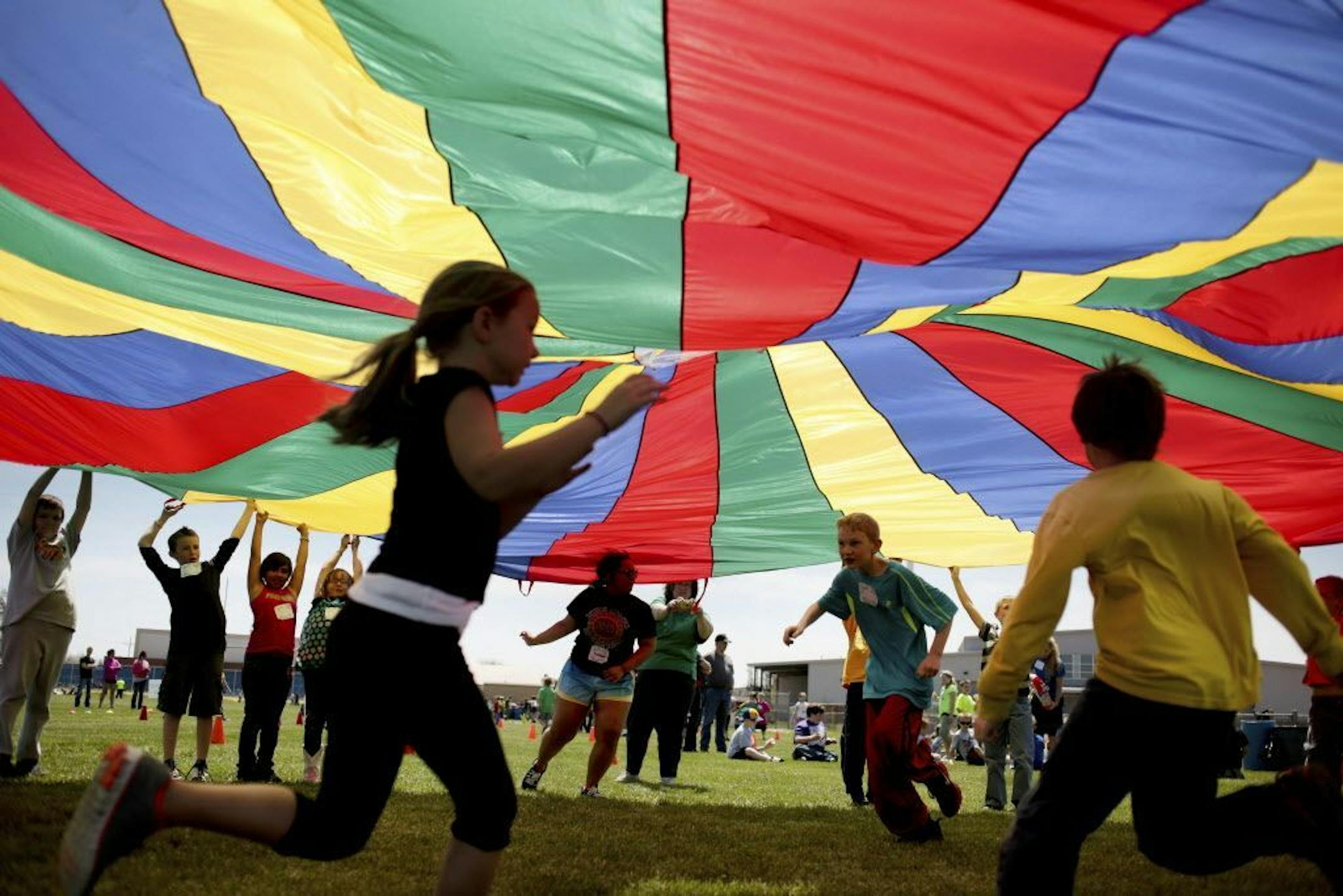 FILE - In this Thursday, April 25, 2013 file photo, elementary school third graders run under a rainbow colored tarp during the 15th Annual Kansas Kids Fitness Day, in Hutchinson, Kan. New federal guidelines released on Monday, Nov. 12, 2018, advise that children as young as age 3 should move more, sit less and get more active, and that any amount and any type of exercise helps health.
