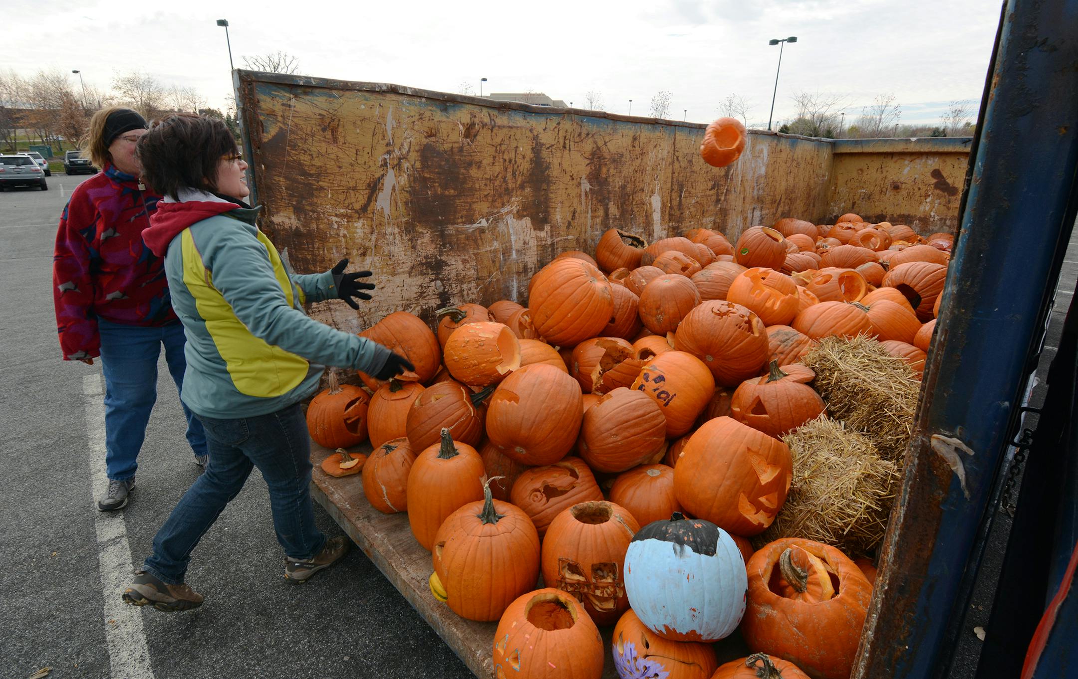 Jane Hubbard, of Rosemount, tosses a pumpkin into the dumpster, while Claudia Zweber, of Eagan, looks on. Photo by Liz Rolfsmeier, Special to the Star Tribune