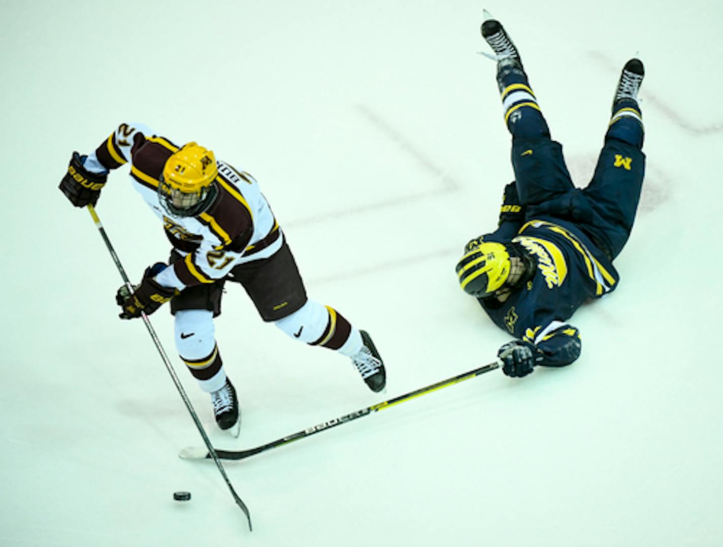 Michigan Wolverines forward Nick Pastujov (91) was upended as he was challenged by Minnesota Golden Gophers forward Nathan Burke (21) for the puck in the third period.   ]   Aaron Lavinsky ¥ aaron.lavinsky@startribune.com