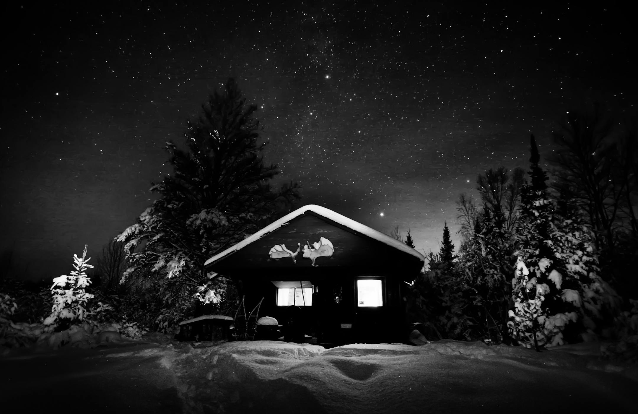 After finding the right composition and a good exposure for the stars, you can use a small flashlight to paint light on the sceen. In this photograph the front of the cabin and trees were lit with a flashlight and the glow from inside the cabin was coming from two small candles. The bright orange glow in the sky above the right corner of the cabin was coming from a town 15 miles away. Camera Data: Canon EOS 5D, ISO 800, f2.8 for 25 seconds with a 16mm lens. ] Northern Minnesota, MN 12/08//2013 O