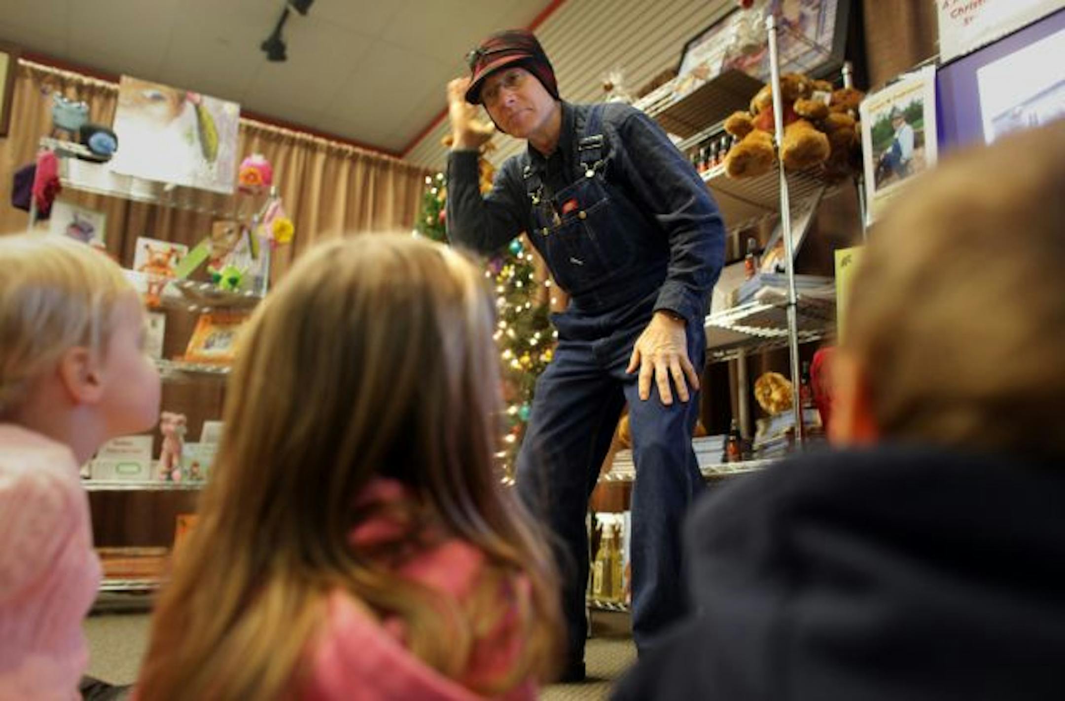Children's author Gordon W. Fredrickson talked to children about what people wear on the farm, like his hat with ear flaps, before reading his book "A Farm Country Christmas Eve" at the Bye Bye Bookstore and the Eden Prairie Center.