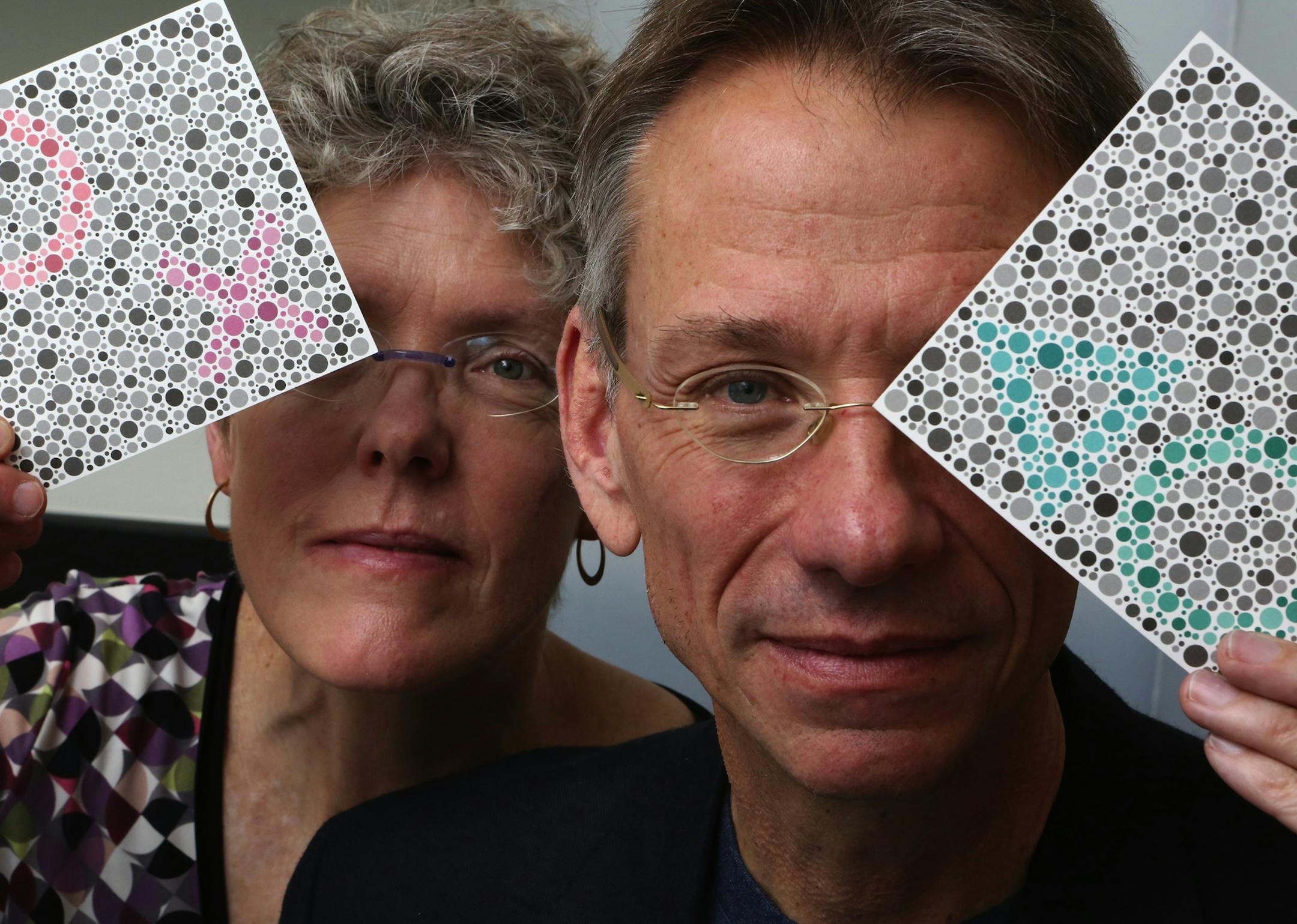 University of Washington researchers Jay and Maureen Neitz, seen holding testing cards for color perception, have teamed up with a California biotech company for a prospective gene-therapy cure for colorblindness. (Ken Lambert/Seattle Times/TNS)